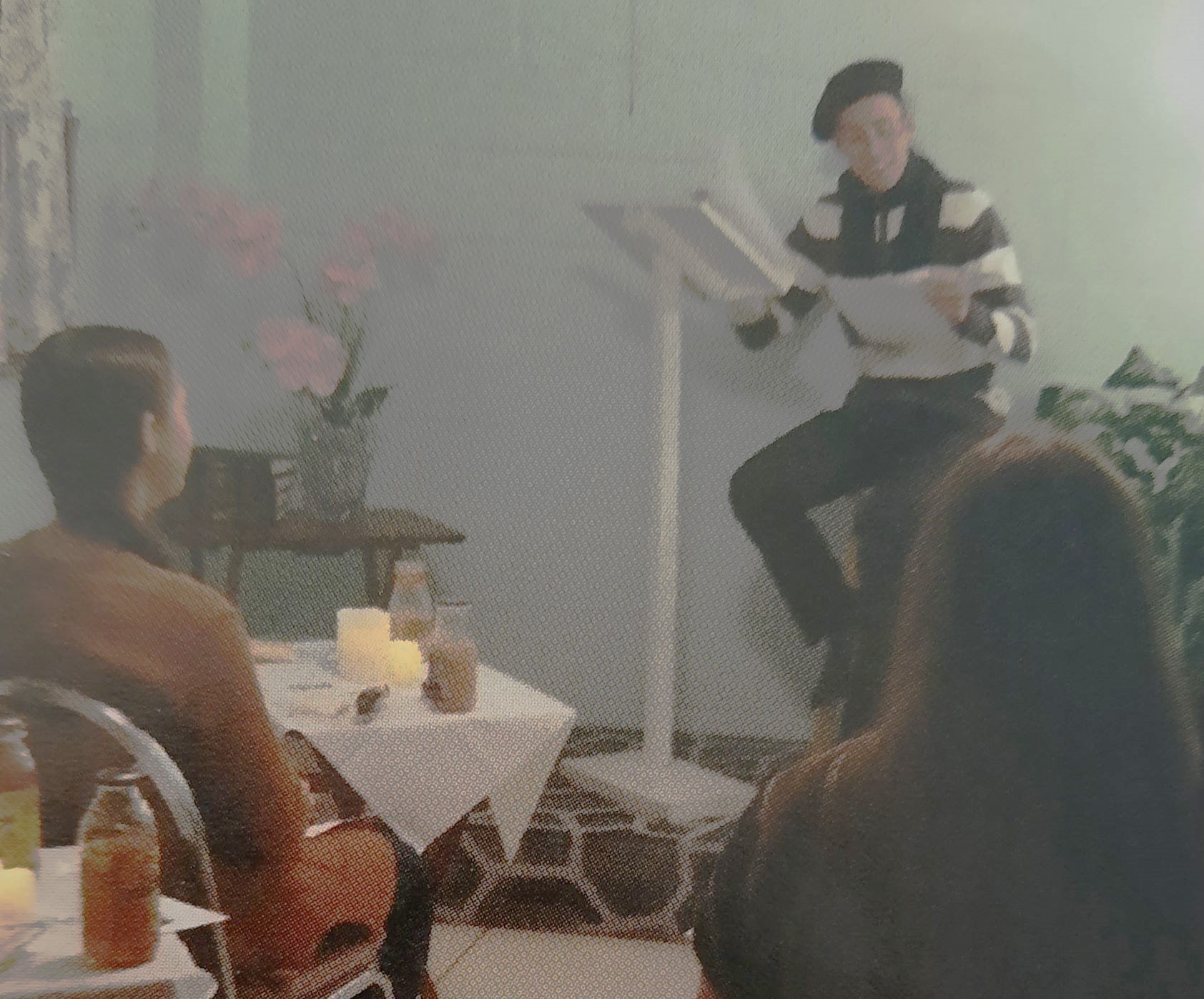 Students sitting at cafe tables watching a student present poetry at a Poetry Cafe - homeschooldrama.com